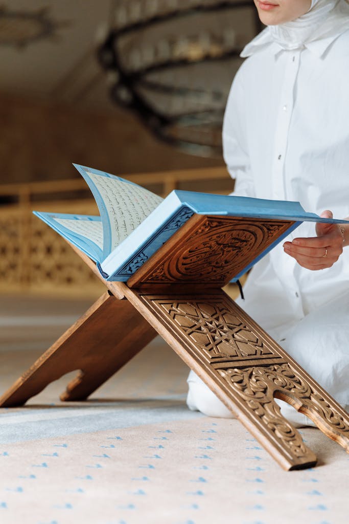 A person reads the Quran inside a mosque with intricate decor, emphasizing Islamic faith and spirituality.