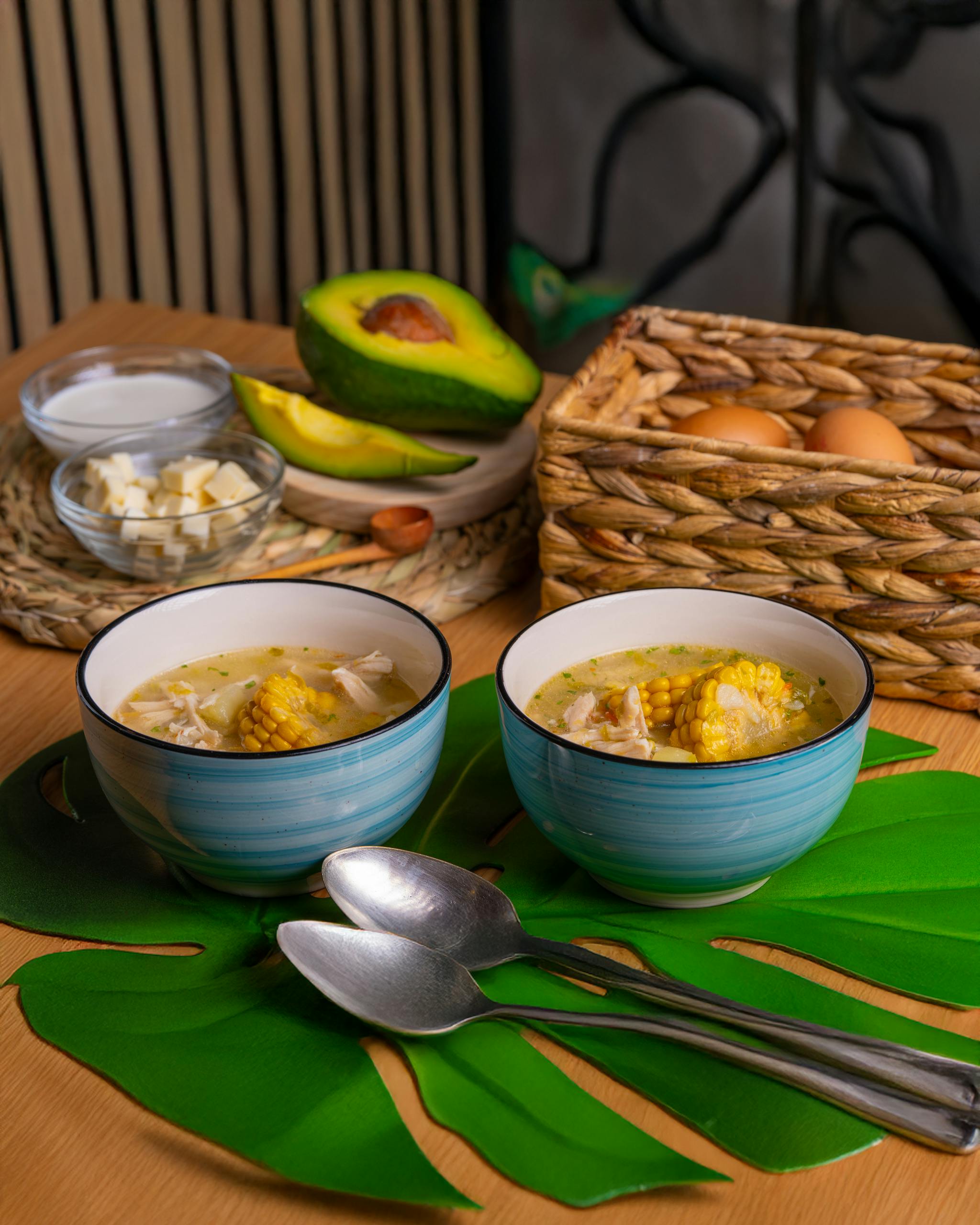 Hearty chicken corn soup with fresh avocado slices and eggs on a cozy table setting.