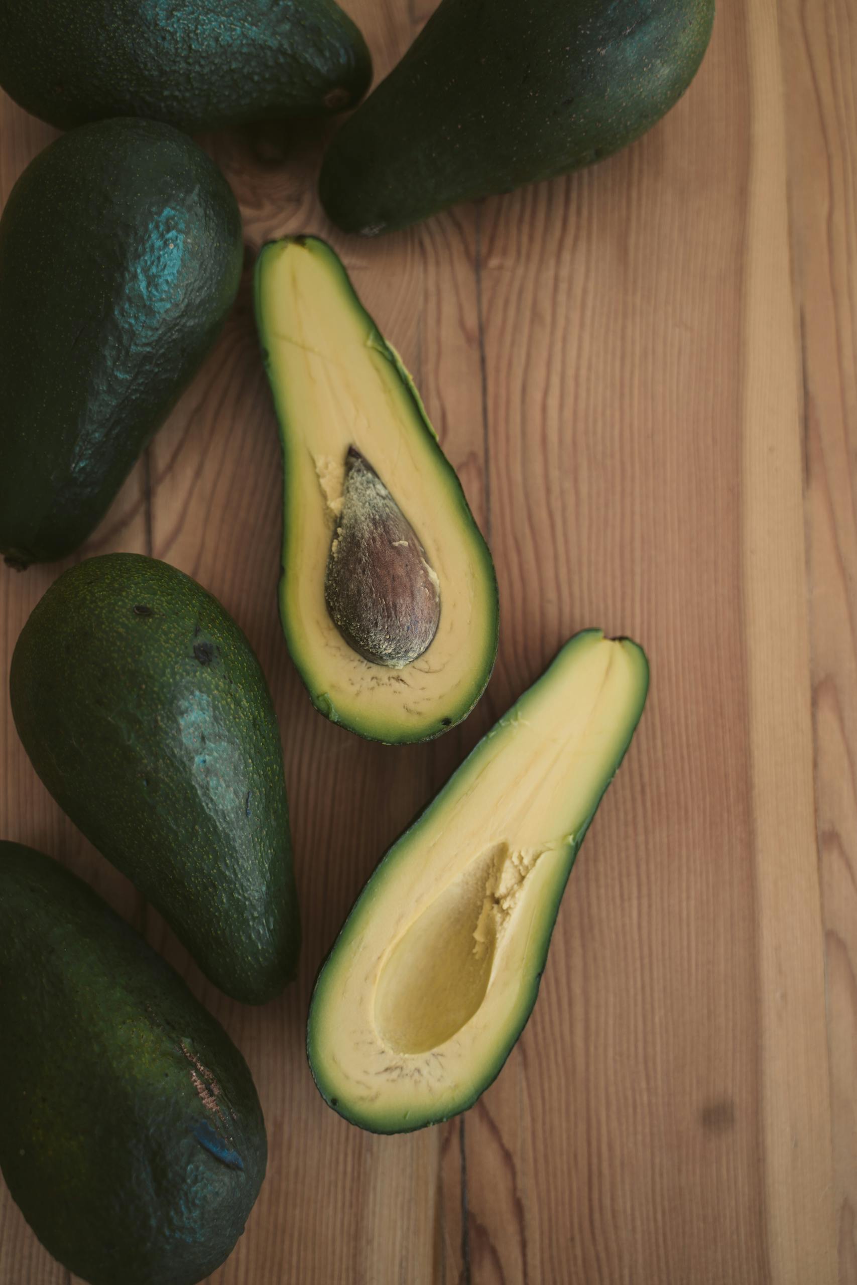 Sliced avocados showcasing fresh, vibrant green flesh on a wooden surface.