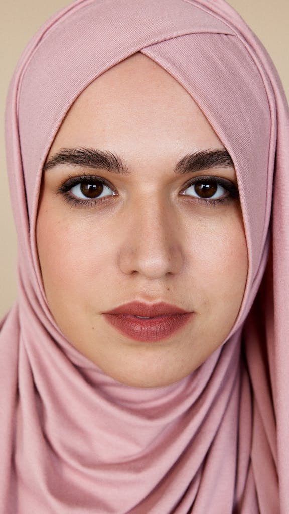 Close-up portrait of a woman wearing a pink hijab, conveying grace and style.