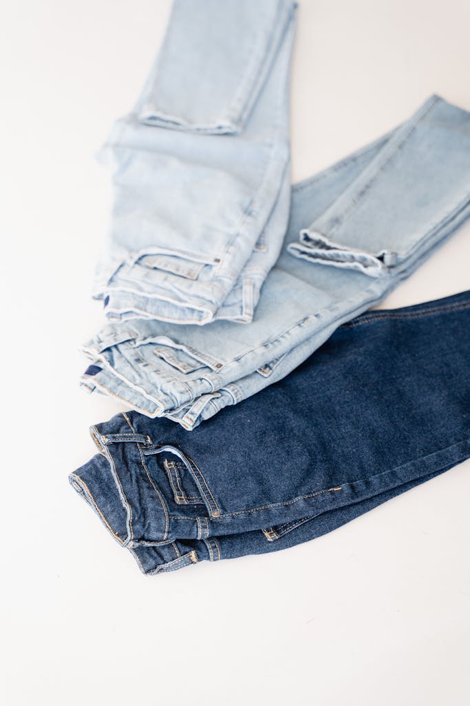 Vertical shot of three denim jeans in light and dark wash for fashion concepts.